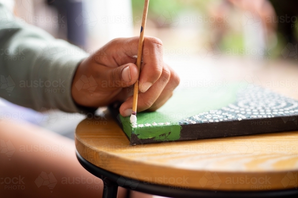 Close-up of a young Aboriginal woman painting - Australian Stock Image