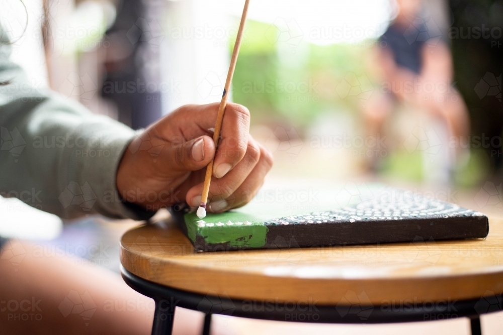 Close-up of a young Aboriginal woman painting - Australian Stock Image