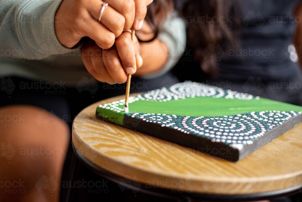 Close-up of a young Aboriginal woman painting - Australian Stock Image