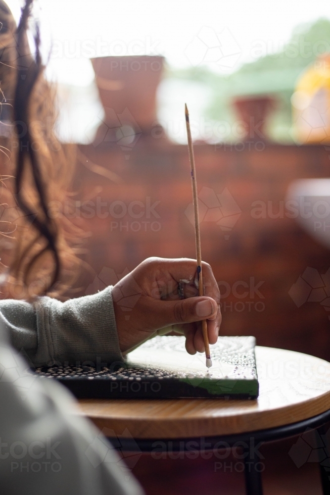 Close-up of a young Aboriginal woman painting - Australian Stock Image