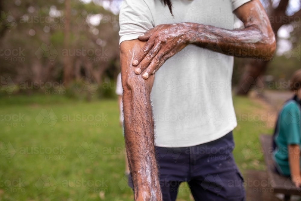 Close-up of aboriginal man applying traditional body paint to his arm - Australian Stock Image