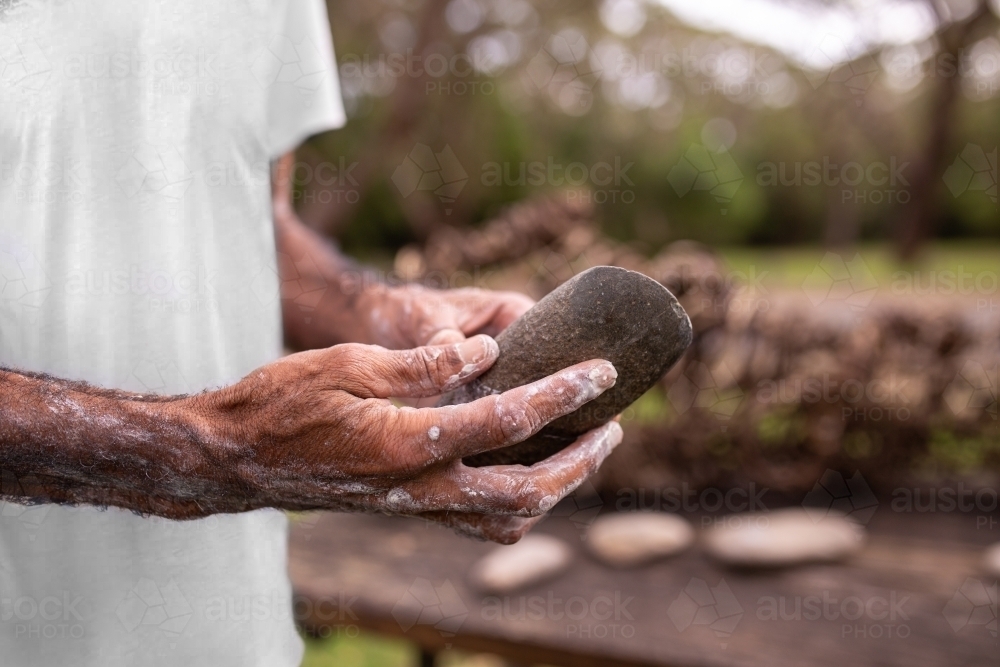 close-up of aboriginal man's hands holding a sacred rock - Australian Stock Image