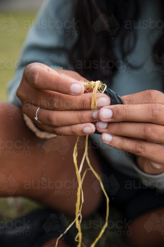 Close-up of an Aboriginal girl weaving threads, making baskets and bangles - Australian Stock Image