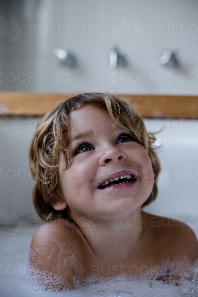 Close up of boy smiling in the bath - Australian Stock Image