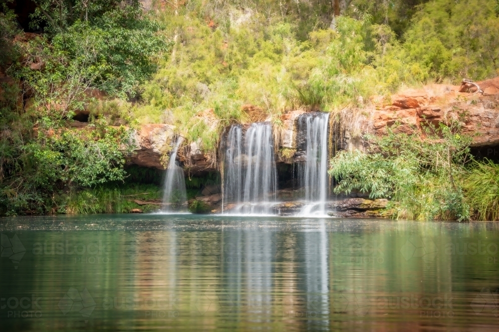 Close up of calm waters and a clear reflection in front of a waterfall - Australian Stock Image