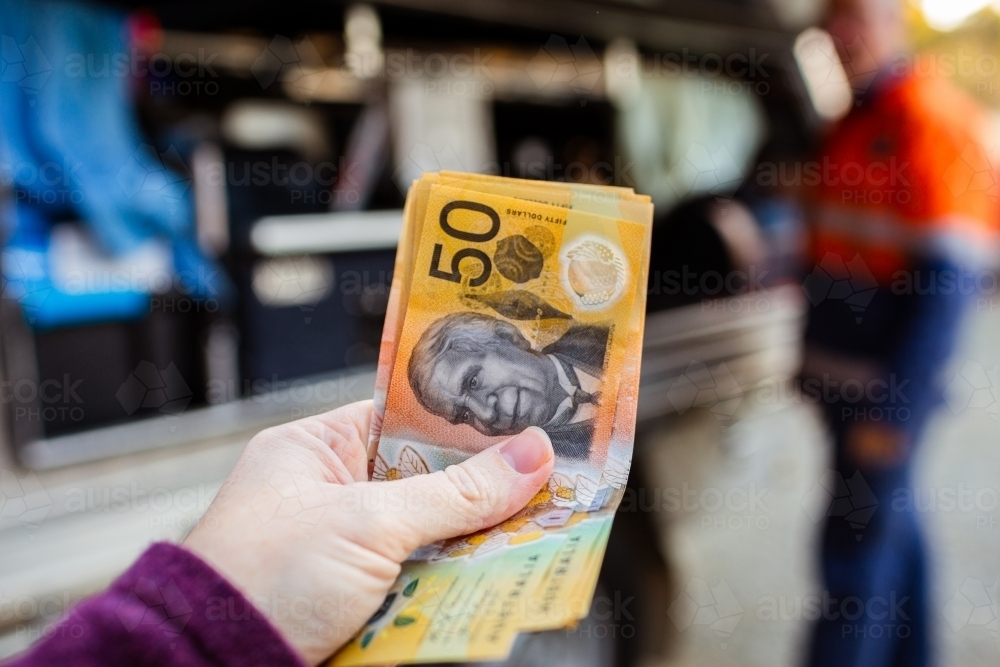 Close up of cash payment in woman's hand to pay tradesman for job - Australian Stock Image