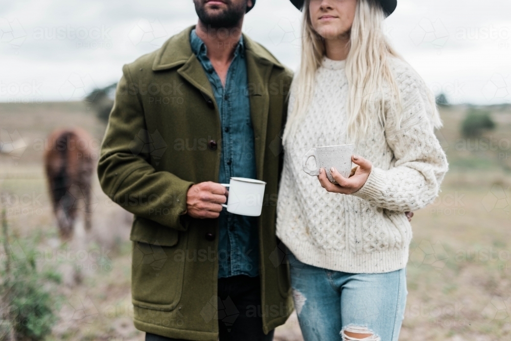 Close up of couple holding cups of coffee outside on farm - Australian Stock Image