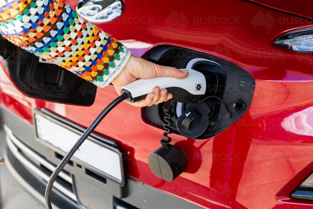 Close up of electric vehicle charging plug being plugged into ev car - Australian Stock Image