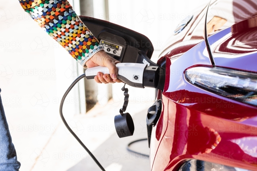 Close up of electric vehicle charging plug being plugged into ev car - Australian Stock Image