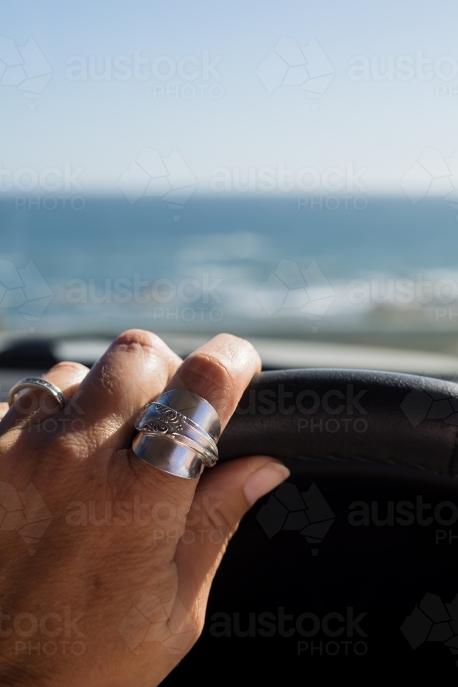 close up of female hand driving near the ocean - Australian Stock Image