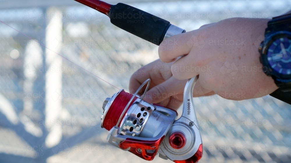 Close up of fishing reel in hand - Australian Stock Image