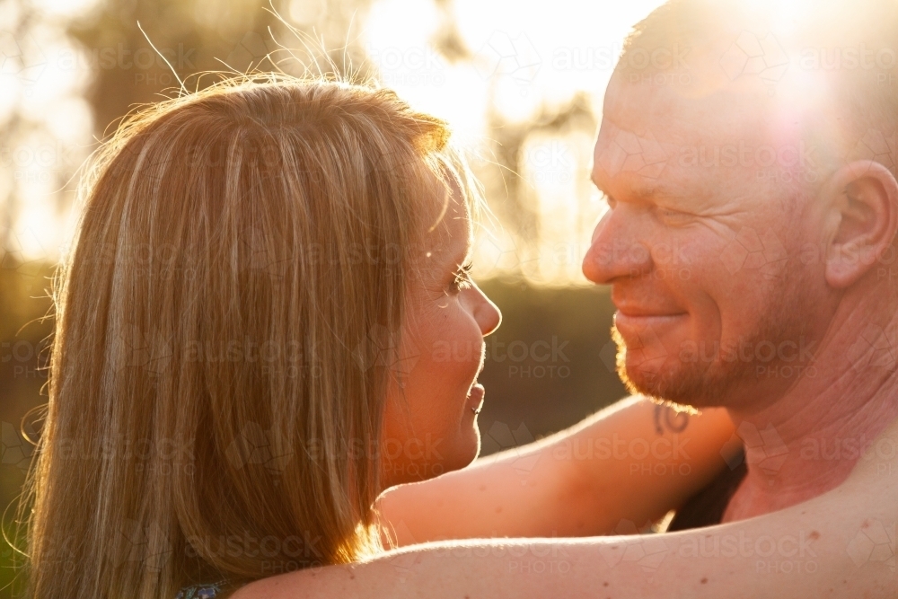 Close up of happy couple looking at one another in beautiful light - Australian Stock Image