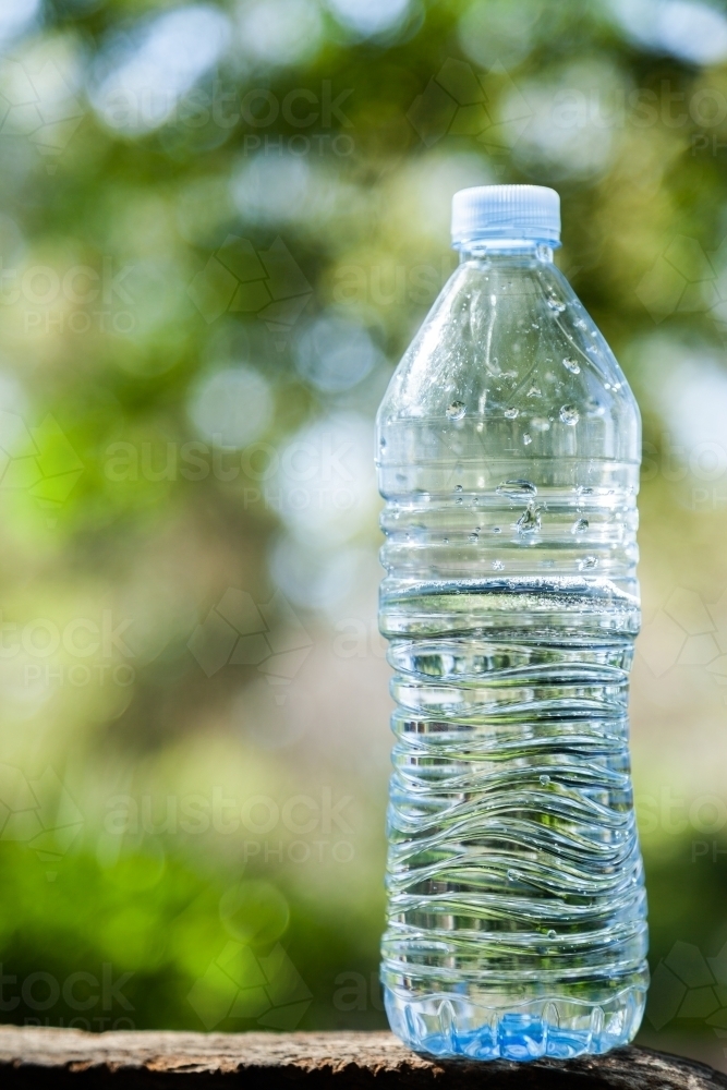 Image of Close up of plastic water bottle outside with green bokeh ...