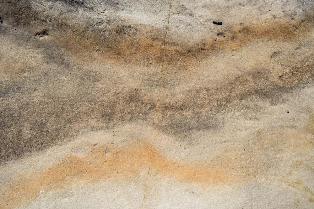 Close up of rock with cream, orange and brown wavey pattern and crack through middle - Australian Stock Image