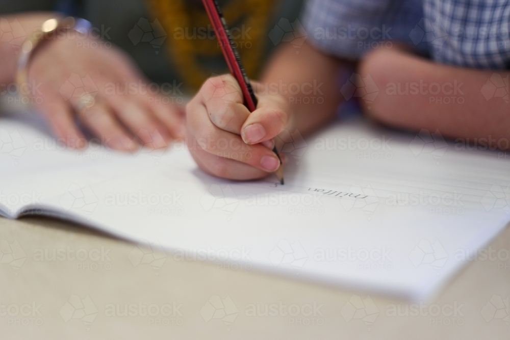 Close up of school girl's hand writing in a book - Australian Stock Image