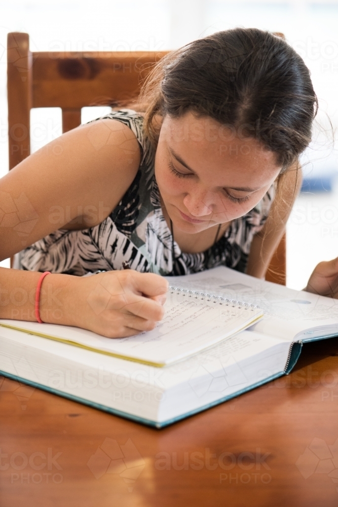 Close up of teenager doing homework at table. - Australian Stock Image