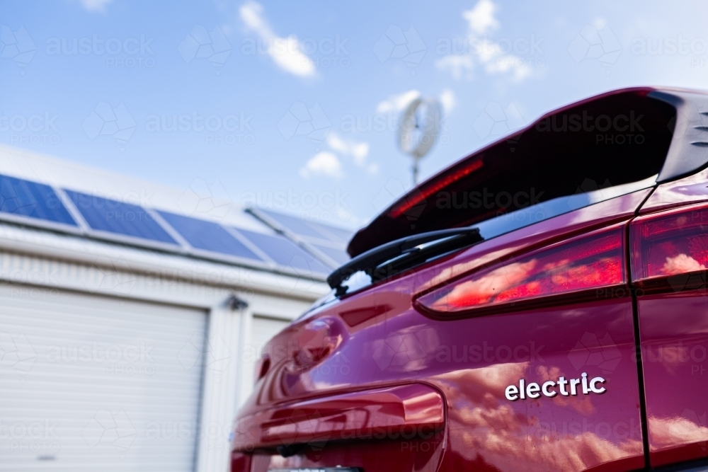 Close up of the word electric on ev car with solar panels and wind turbine - Australian Stock Image