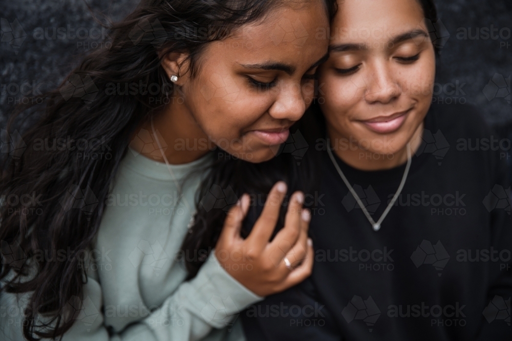 Close-up of two Aboriginal girls hugging - Australian Stock Image