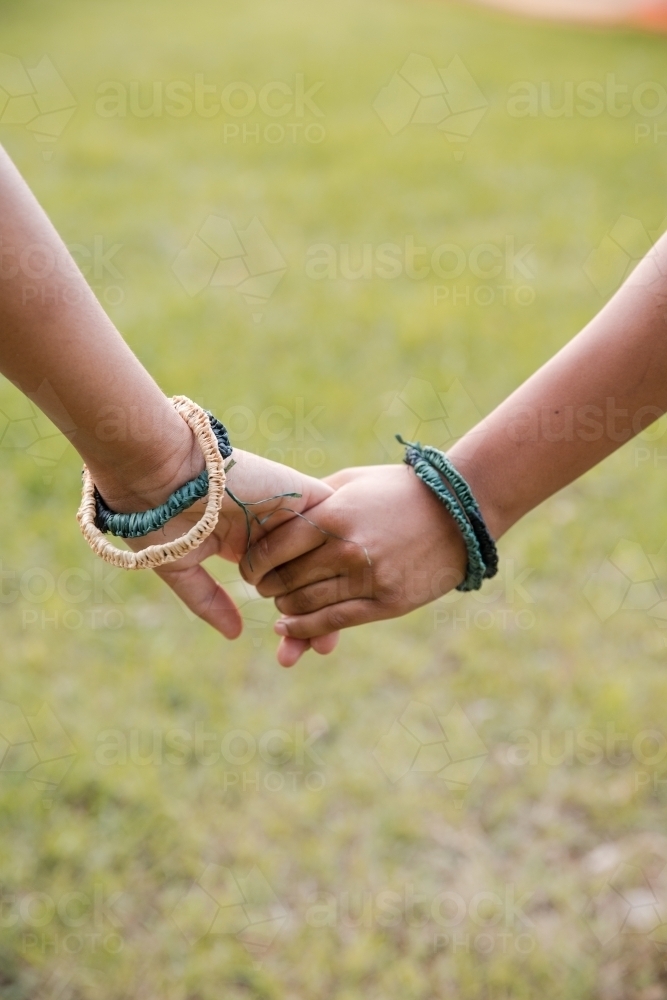 Close-up of two Aboriginal girls wearing traditional woven fibre braclets - Australian Stock Image