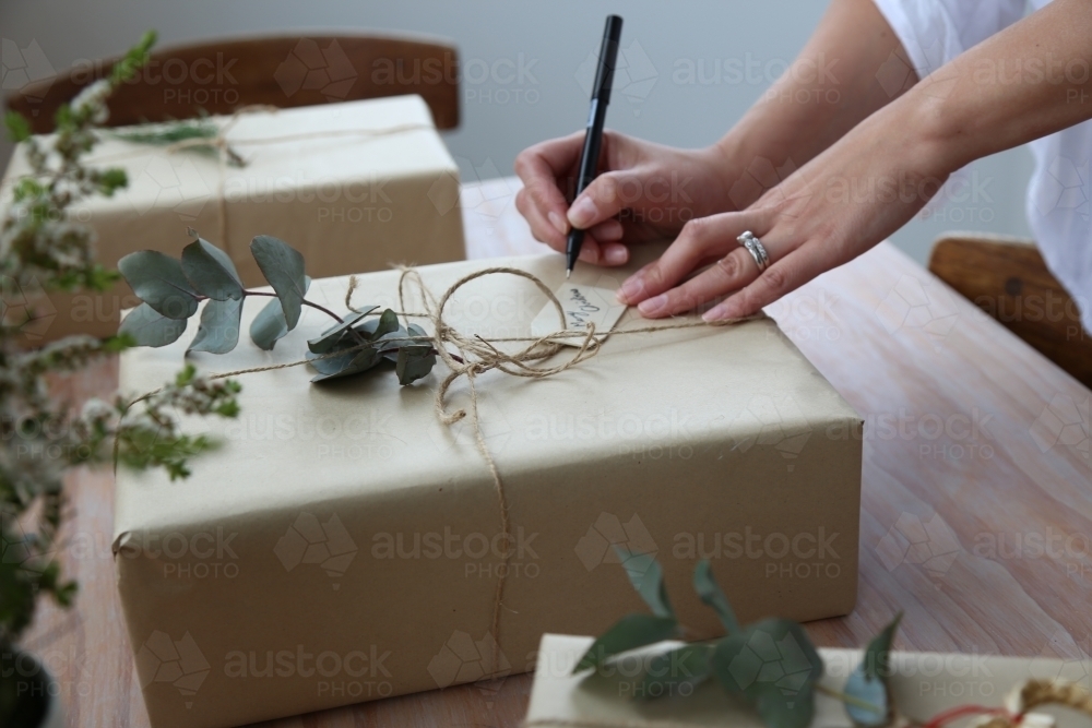 Close up of woman's hands writing gift card for present - Australian Stock Image