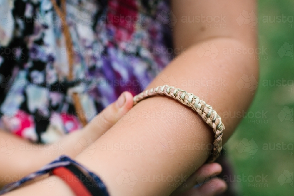 Close-up on a woven bracelet on a childs arm. - Australian Stock Image