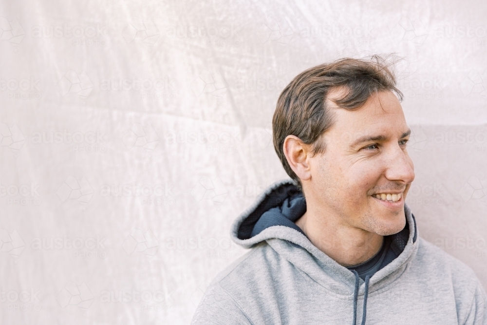 Close up photo of a young sportsman wearing a grey hoodie and smiling - Australian Stock Image