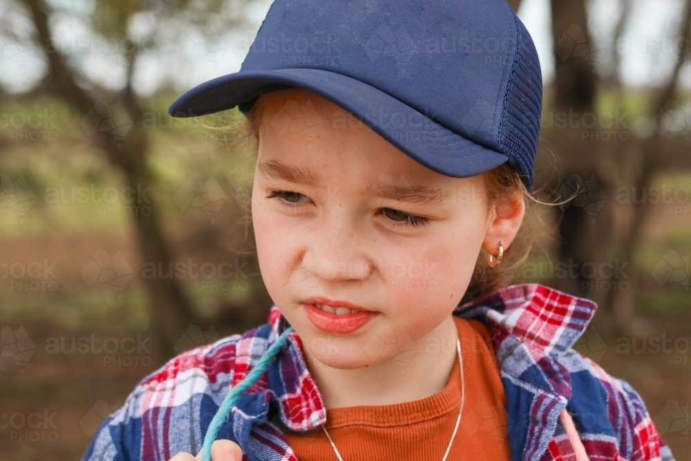 Close up portrait of country girl wearing blue hat and flannelette shirt on farm - Australian Stock Image