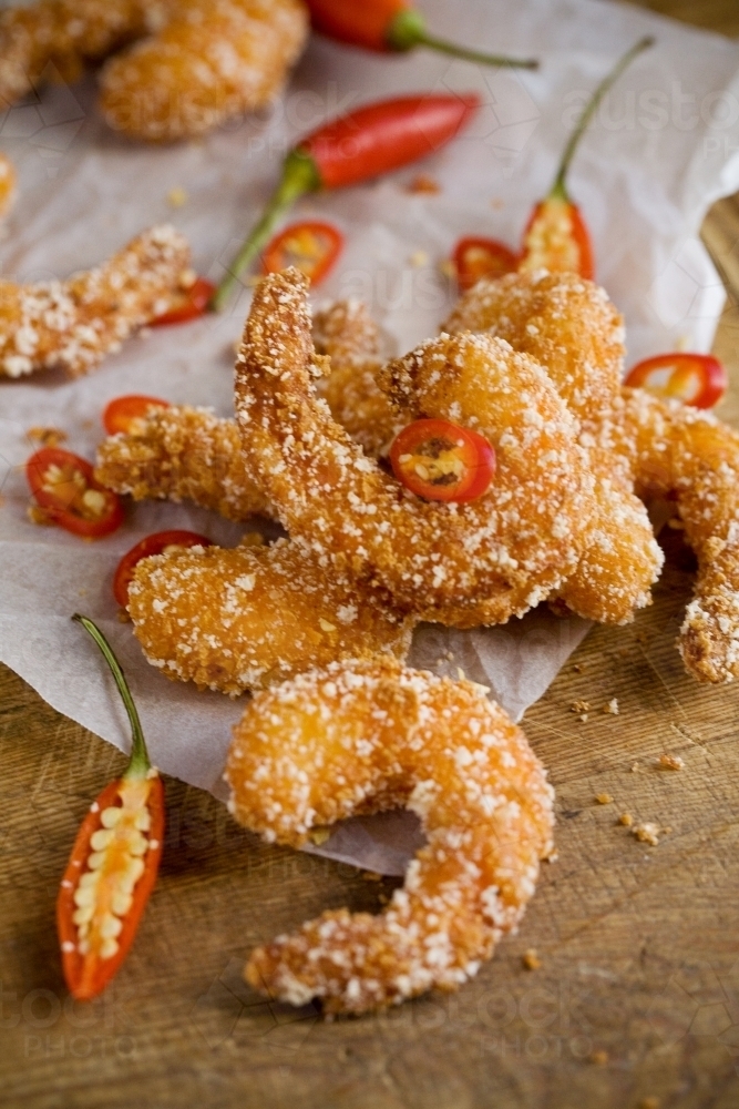 Close up shot of a fried shrimp with white sprinkles on  it and a chopped chili around it - Australian Stock Image