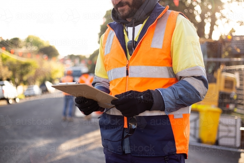 Close up shot of a man road worker with beard wearing high-vis workwear holding his notes - Australian Stock Image