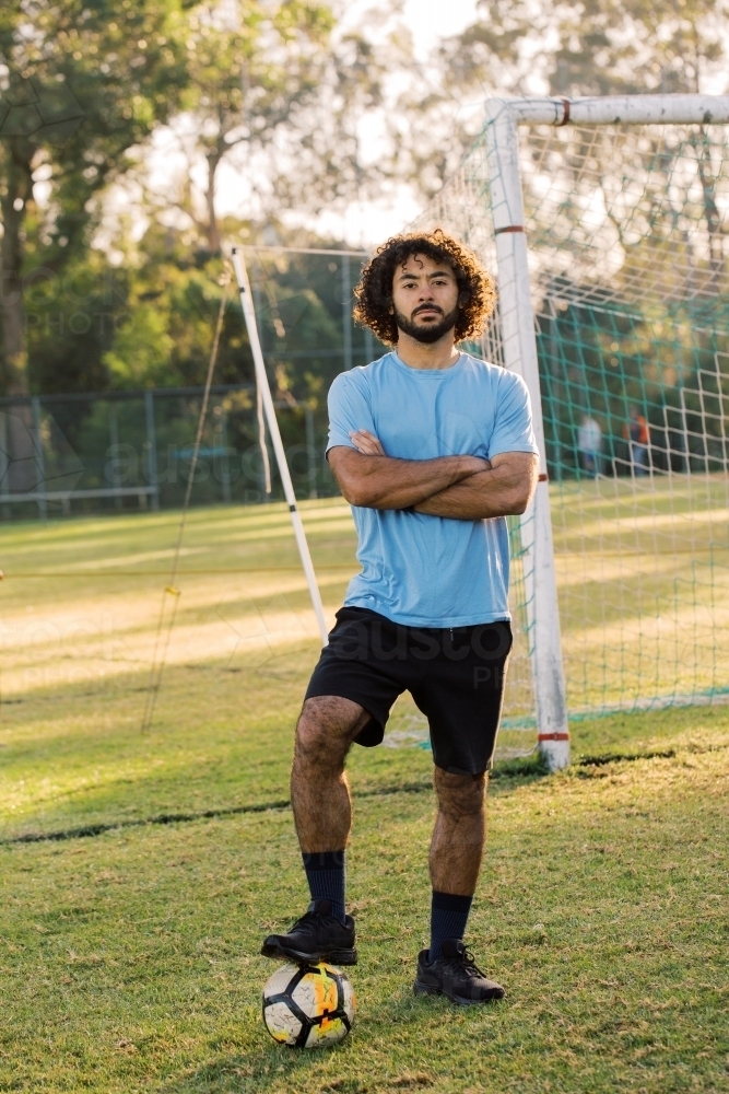 Close up shot of a man standing on the field with a ball on his left foot - Australian Stock Image