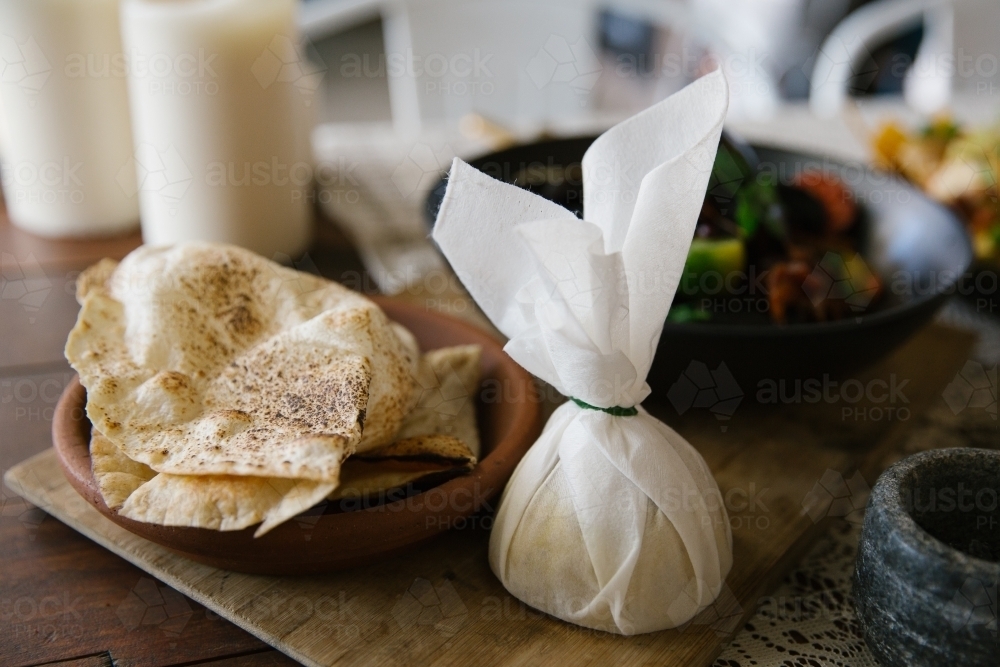 Close up shot of a plate of flat pita bread and a lemon wrapped in a white cloth - Australian Stock Image