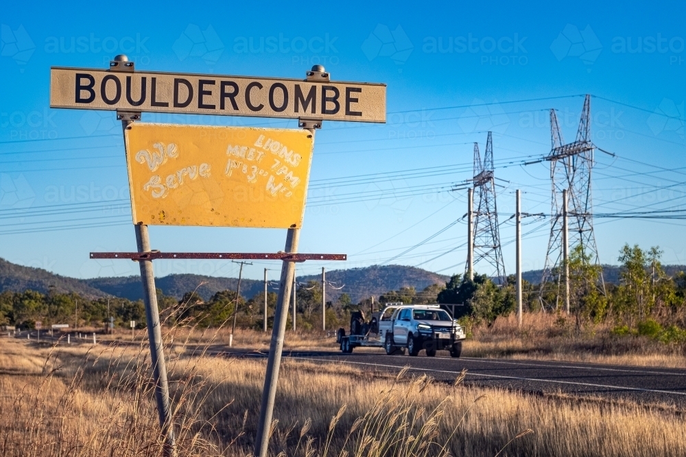 Close up shot of a signage on the roadside and a highway with a car - Australian Stock Image