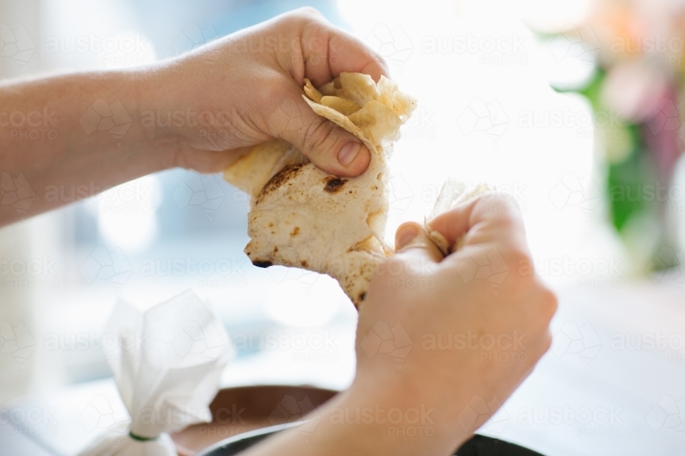 Close up shot of hands tearing a pita bread - Australian Stock Image