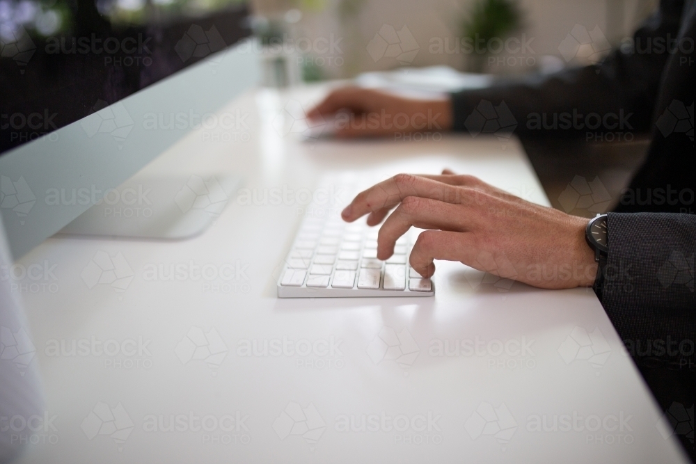 Close-up shot of man's hands typing on a keyboard - Australian Stock Image