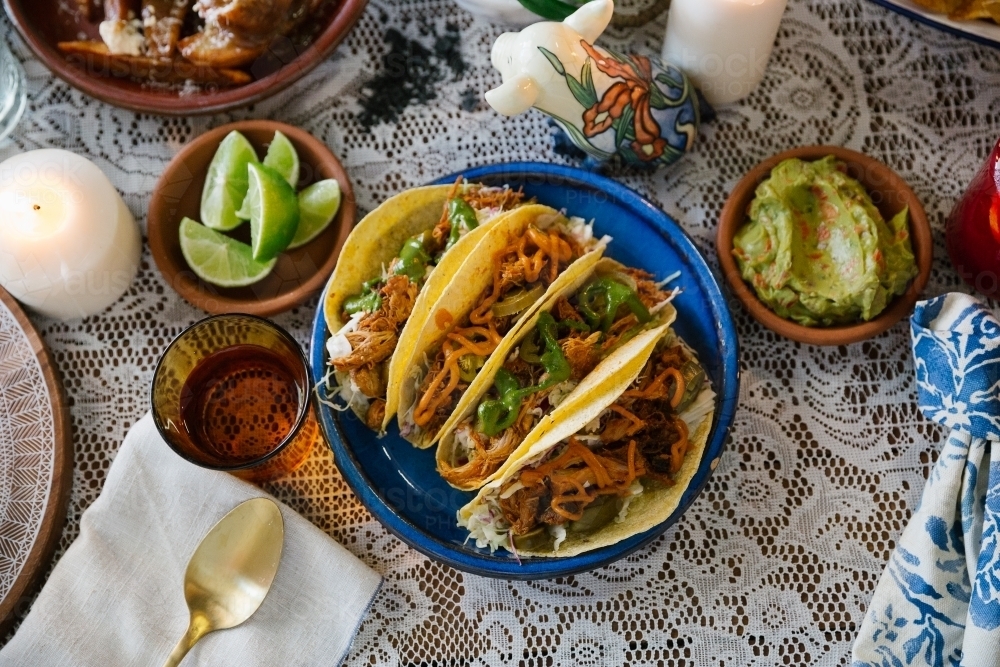 Close up shot of tacos on a blue plate with green citrus and guacamole on the sides - Australian Stock Image