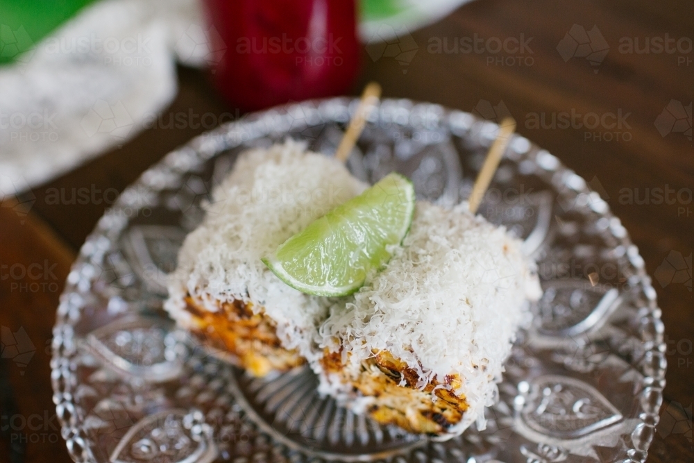 Close up shot of two cobs of chargrilled corn topped with cheese and lime - Australian Stock Image