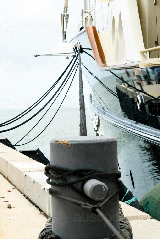 Close up view of bollard and yacht moored at wharf - Australian Stock Image