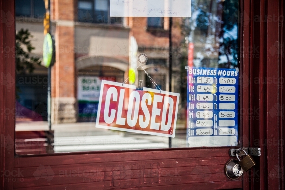 Closed sign hanging in front window of shop - Australian Stock Image