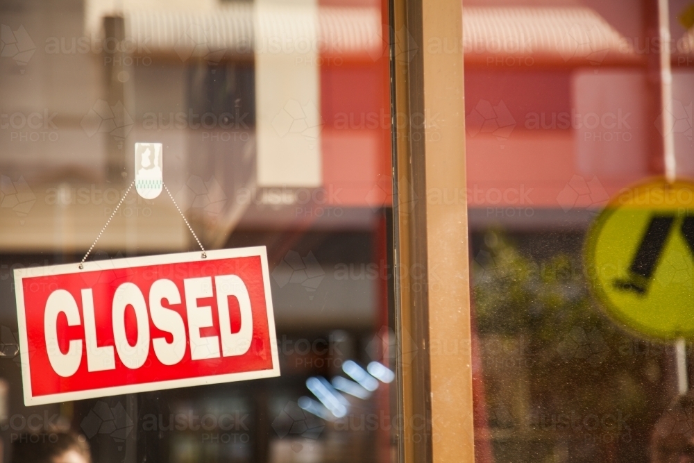 Closed sign hanging in front window of shop - Australian Stock Image