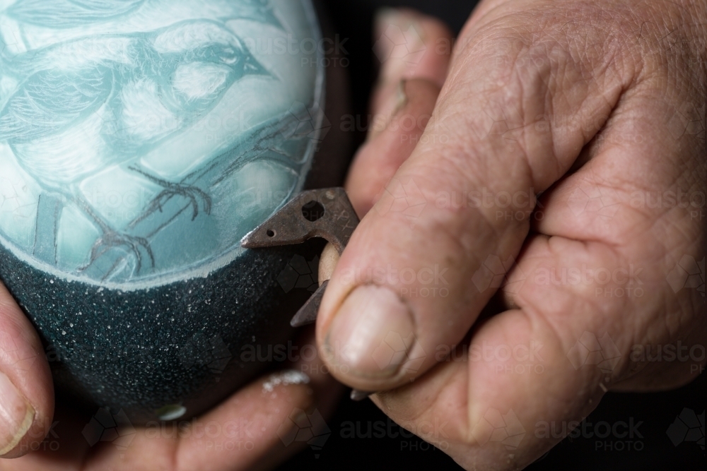 Closeup of man's hands engraving image on emu egg shell - Australian Stock Image