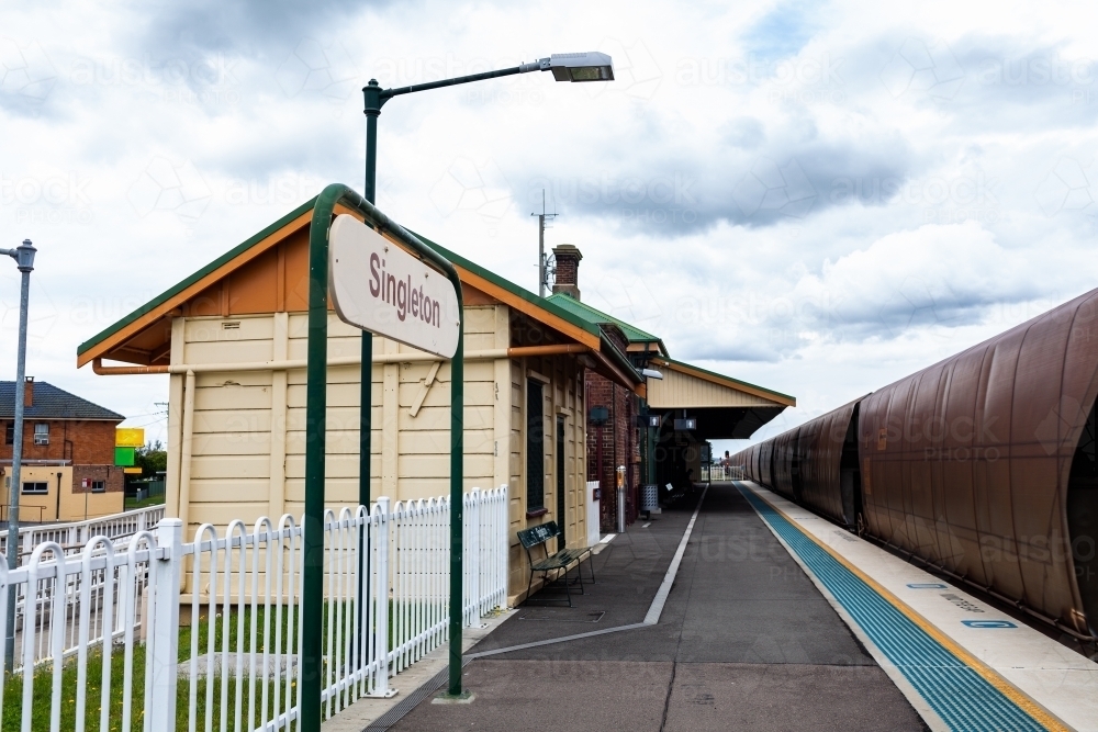 Coal train passing singleton train station railway platform on overcast day - Australian Stock Image