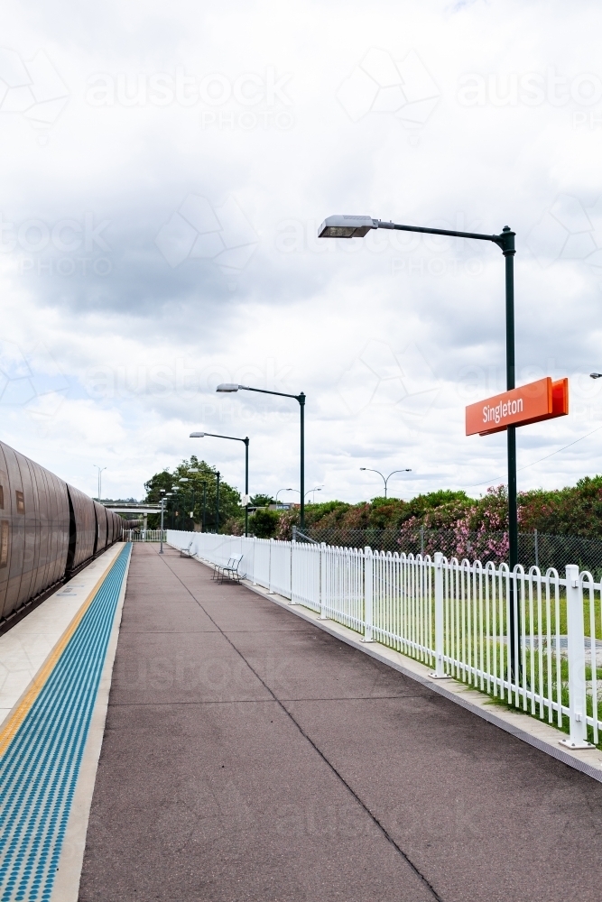 Coal train passing singleton train station railway platform on overcast day - Australian Stock Image