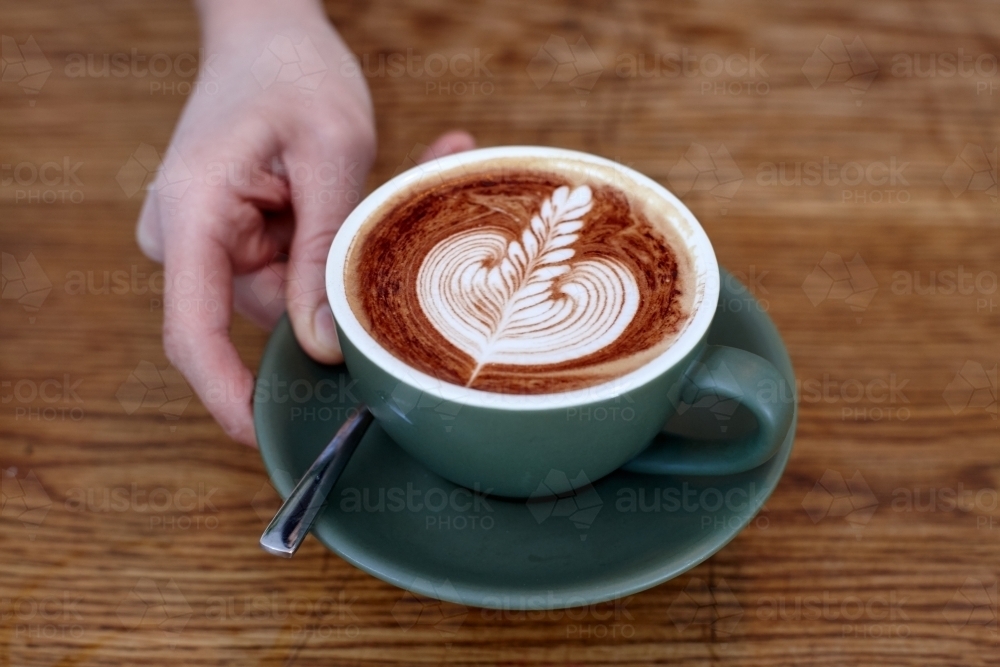 Coffee with froth decoration served on table - Australian Stock Image