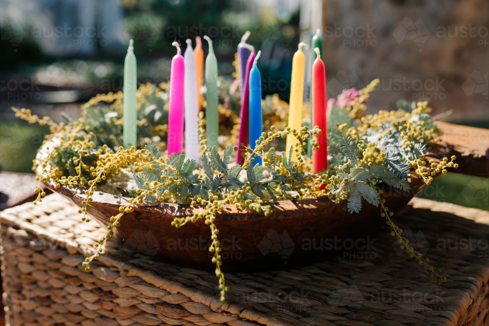 Colourful candles in a dish with yellow flowers. - Australian Stock Image