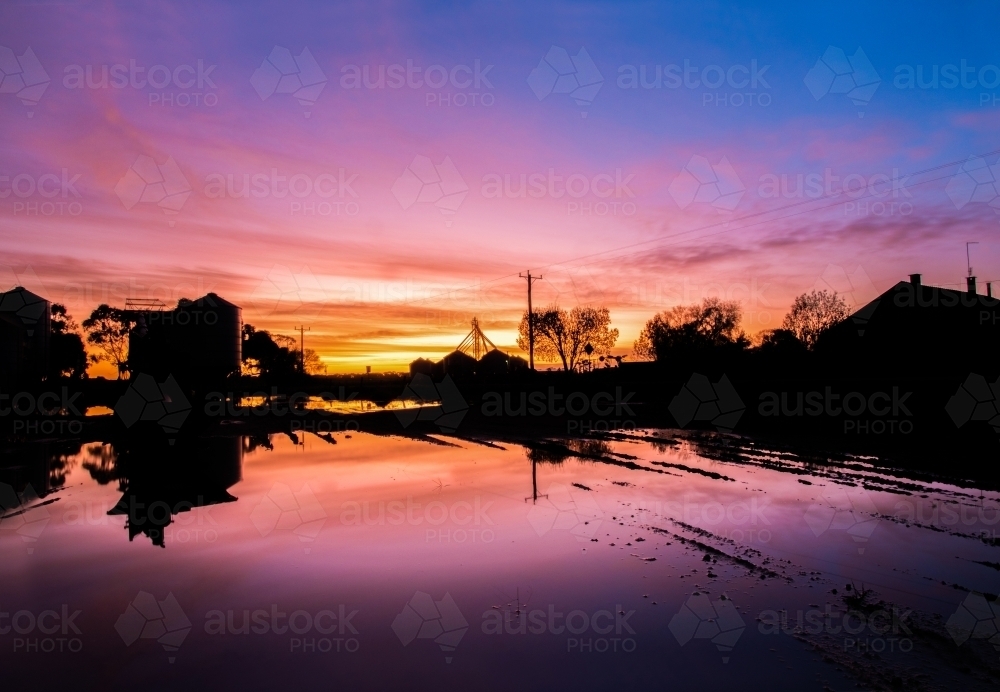 Colourful dawn with water reflections and silo silhouettes. - Australian Stock Image