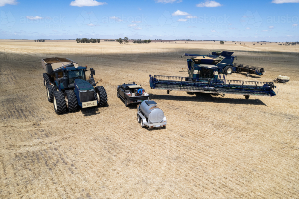 Combine harvester and tractor parked on the crop field - Australian Stock Image