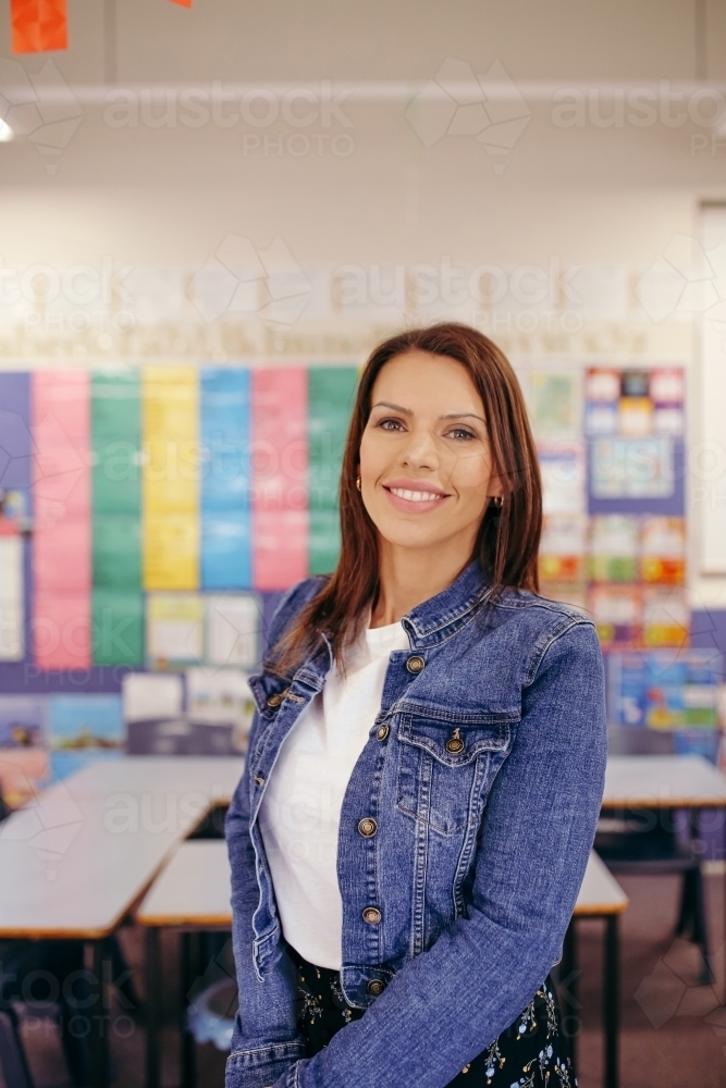 Confident Aboriginal female primary school teacher standing in her classroom - Australian Stock Image