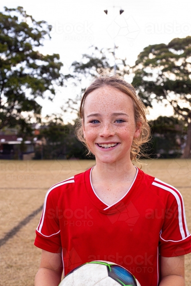 Confident child tween smiling holding a soccer ball - Australian Stock Image