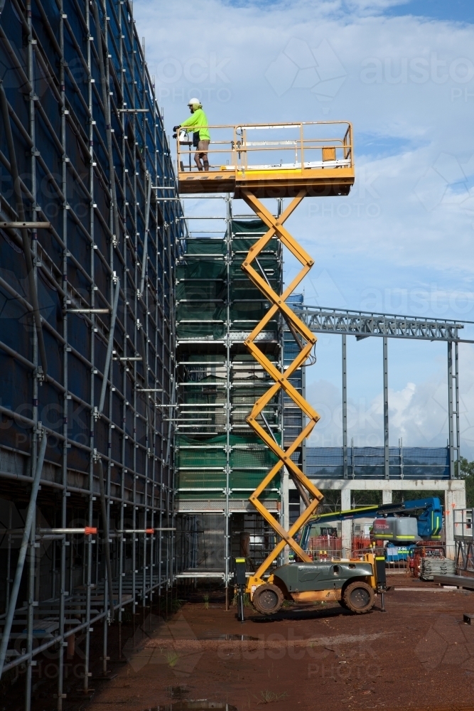 Construction worker on a scissor lift on an industrial building site - Australian Stock Image