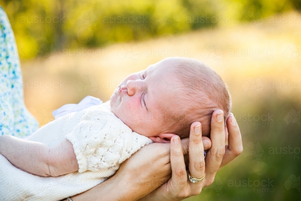 Content sleepy baby in mothers arms - Australian Stock Image